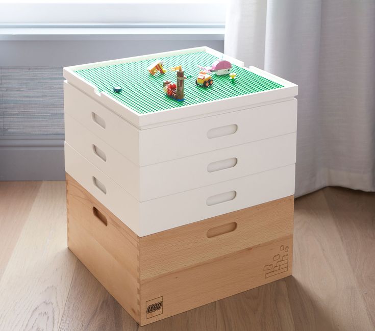 a toy chest sitting on top of a hard wood floor in front of a window