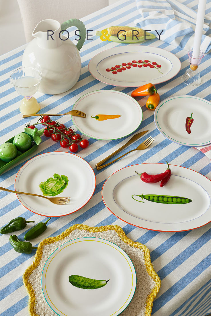 there are many plates on the table with peppers painted on them and some spoons