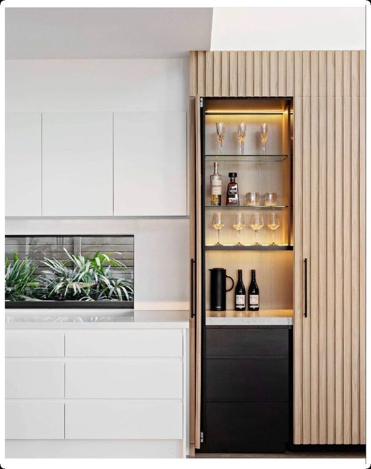 an open cabinet in the middle of a kitchen filled with bottles and glasses on it