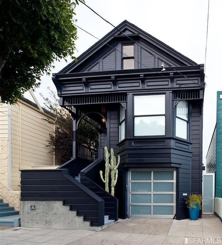 a black house with a cactus in the front yard and stairs leading up to it