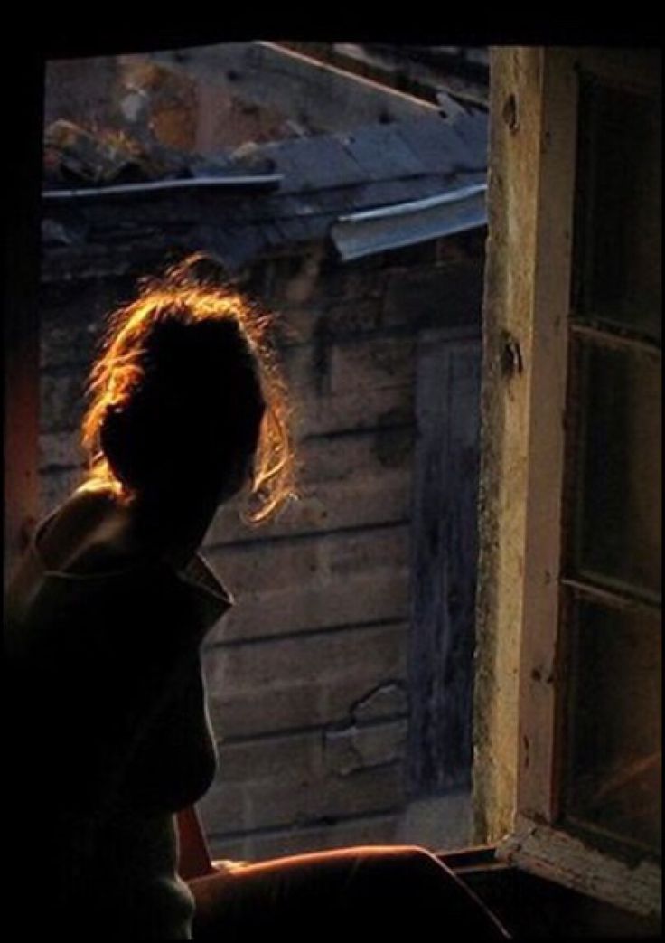 a woman looking out an open window at another person