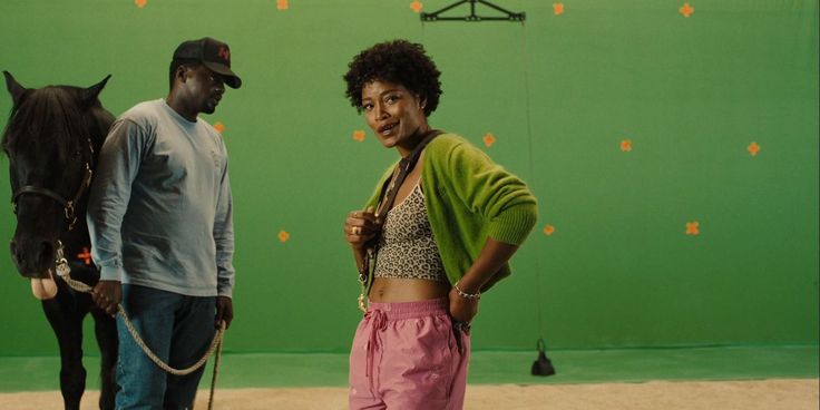 two people standing in front of a green screen with a horse