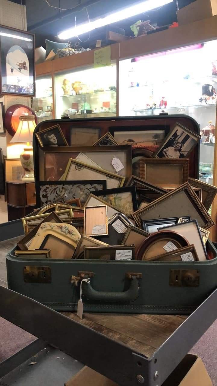 an open suit case filled with assorted items on top of a wooden table in a store