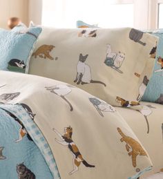 a bed covered in lots of cats on it's covers and pillowcases