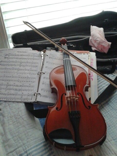 a violin and music sheets on a bed