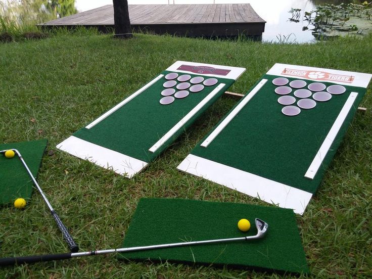 two giant cornhole game boards laying on the grass next to golf balls and tees