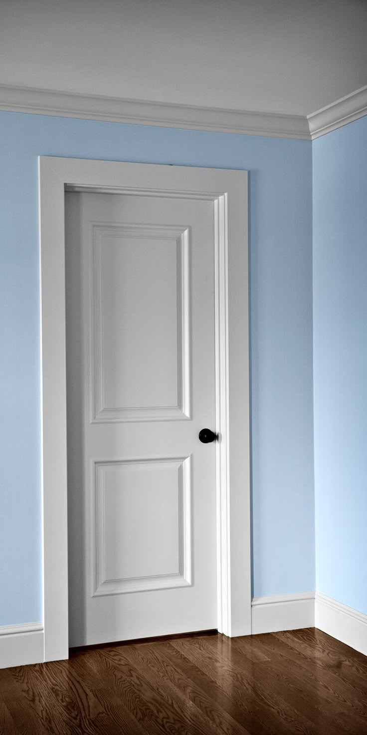 an empty room with a white door and blue walls