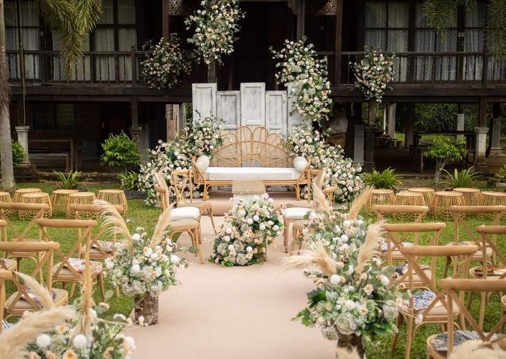 an outdoor wedding setup with chairs and flowers on the aisle, surrounded by greenery