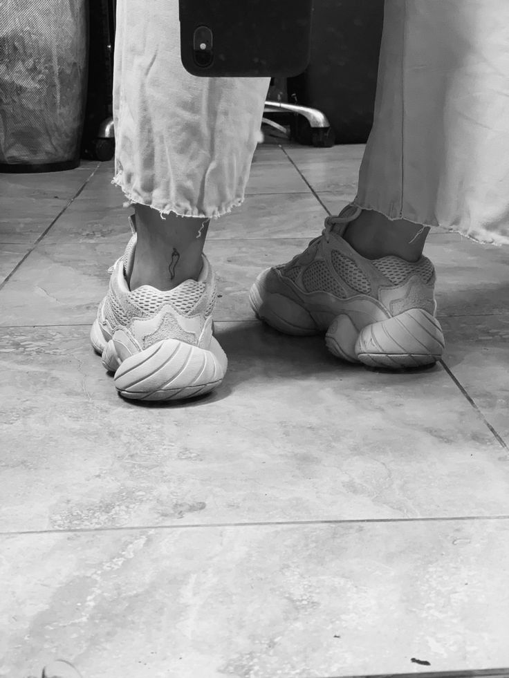 black and white photograph of people's feet in sneakers