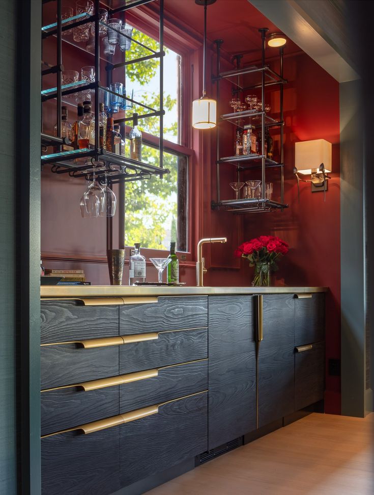 a kitchen with wooden cabinets and glass shelves on the wall, next to a window