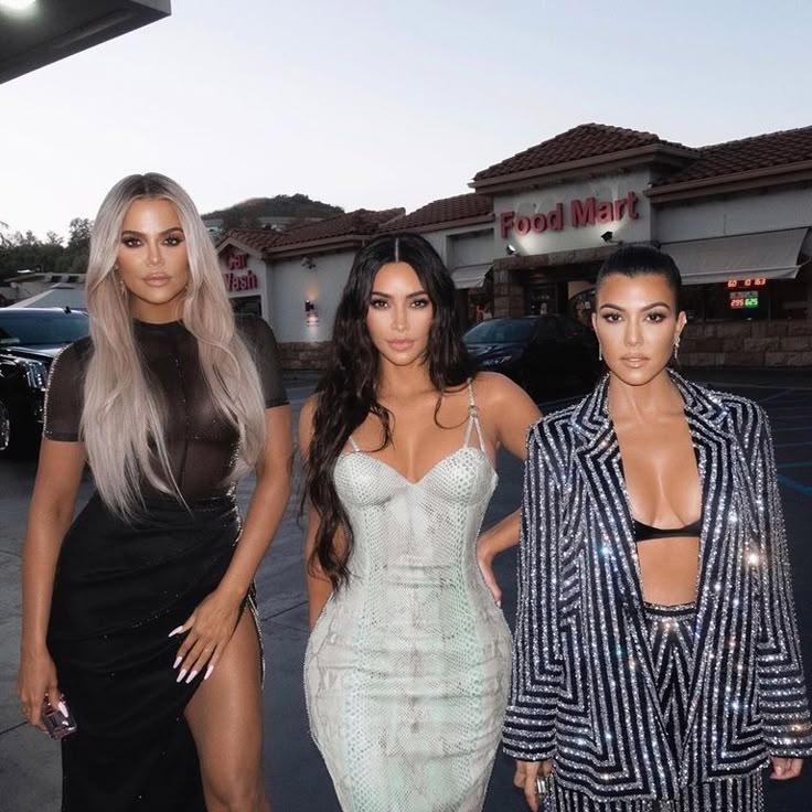 three women standing next to each other in front of a store with their dresses on