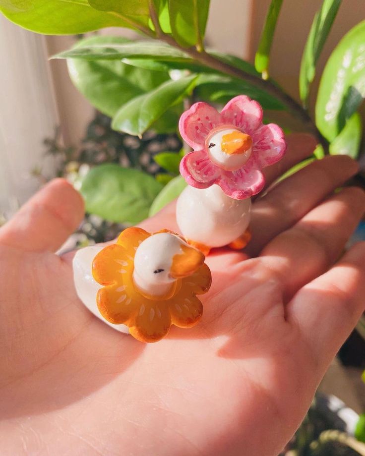 a hand is holding two small figurines with flowers on them