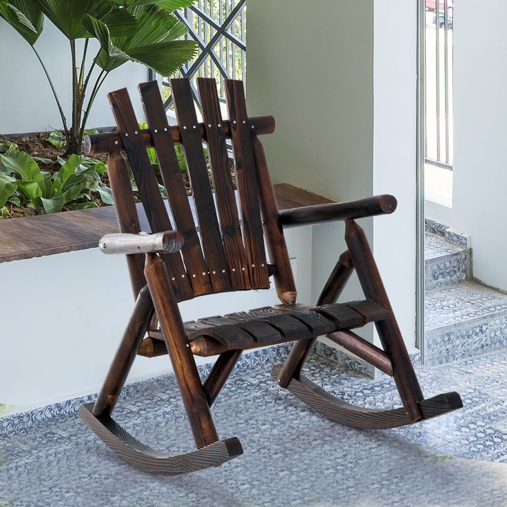 a wooden rocking chair sitting on top of a tiled floor next to a potted plant