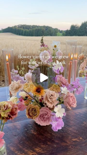 a table topped with vases filled with flowers next to candles and an image of a field