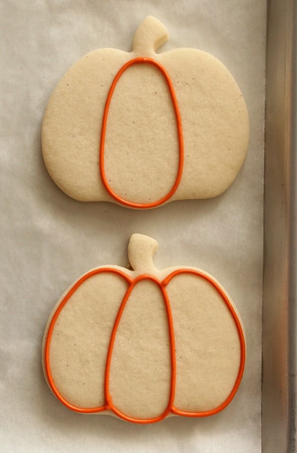 two decorated cookies in the shape of pumpkins