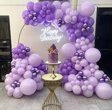 purple balloons are arranged around a cake on a stand