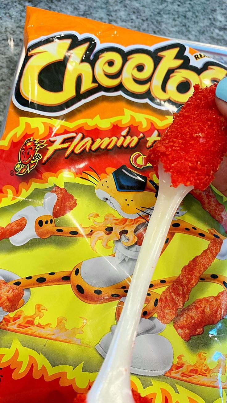 a person holding a candy bar with cheetos on it