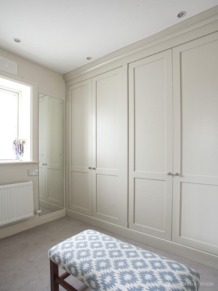 an empty room with white cabinets and a blue bench in front of the window on the far wall