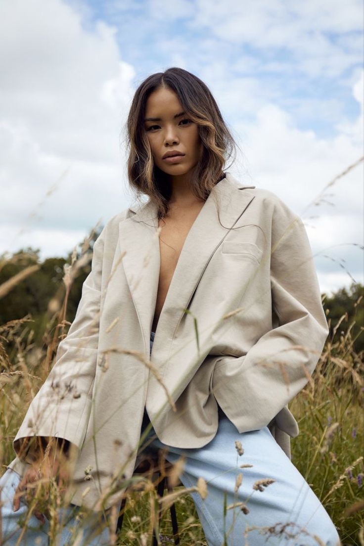 a woman standing in tall grass with her hands on her hips