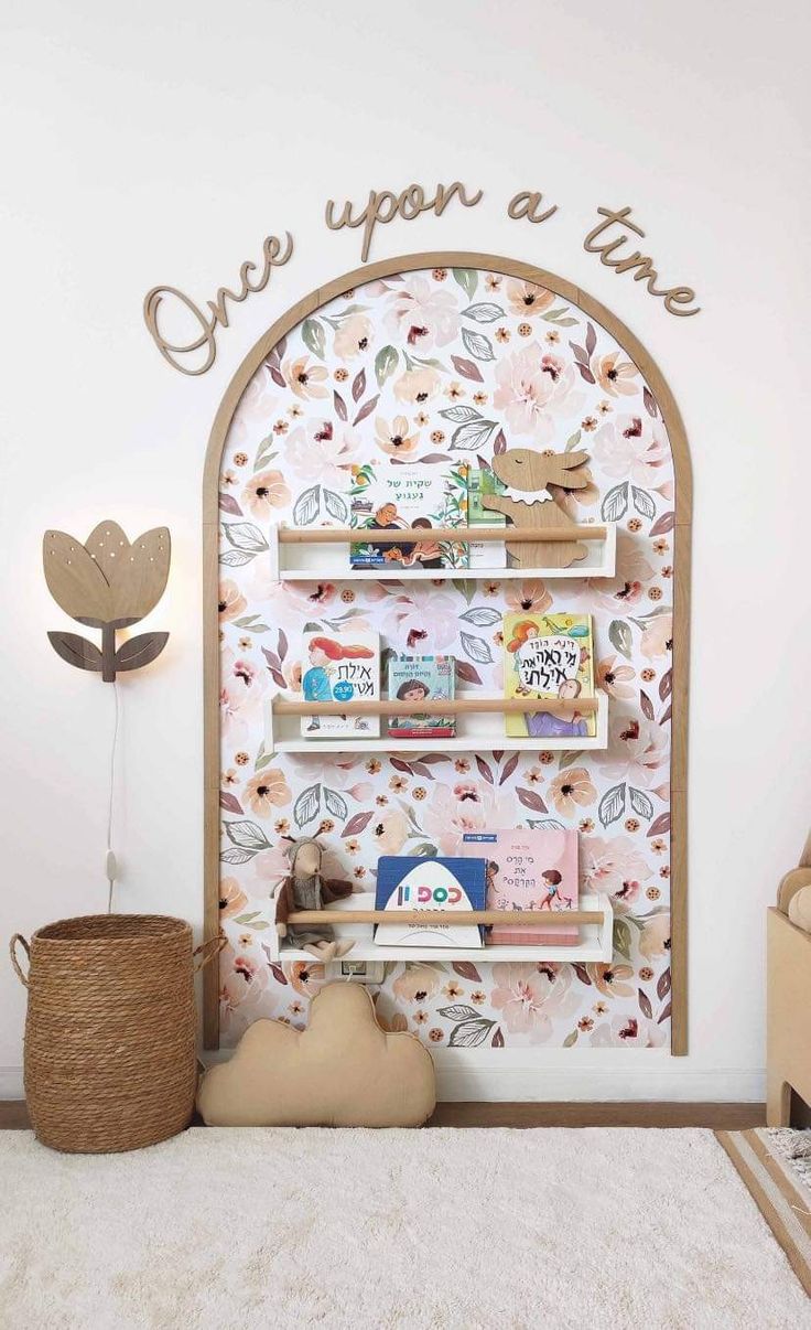 a children's book shelf with books and toys on it in front of a flowered wall