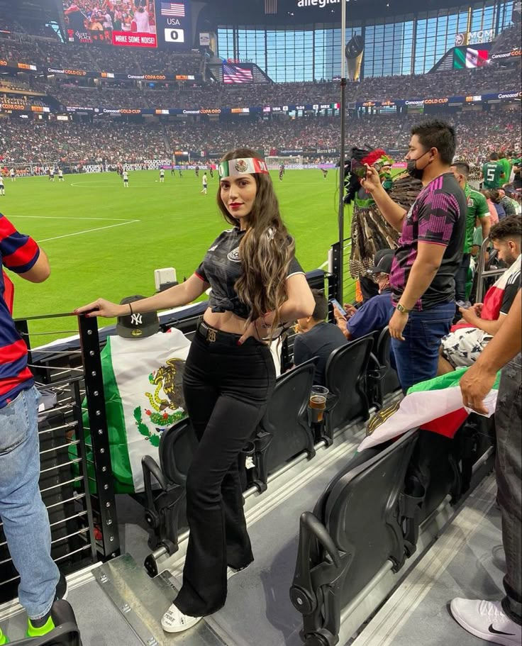 a woman is standing in the stands at a soccer game