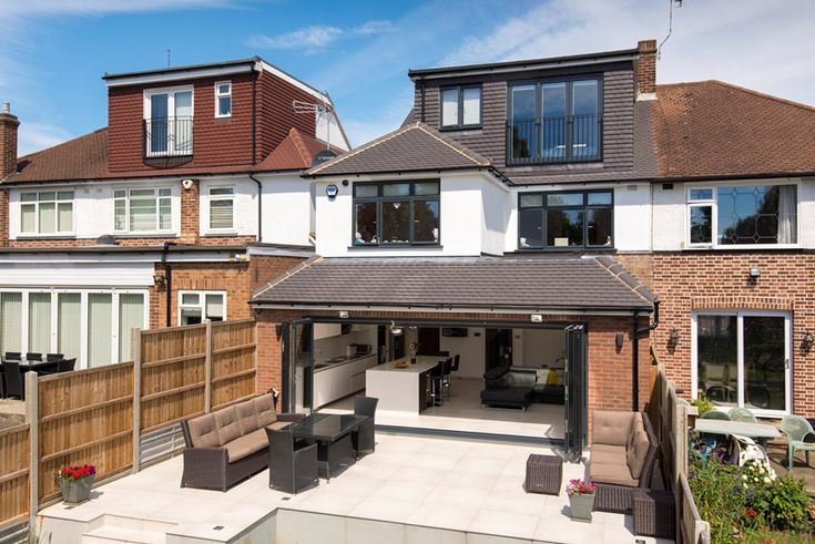 an outdoor living area with patio furniture in front of a large brick building on a sunny day