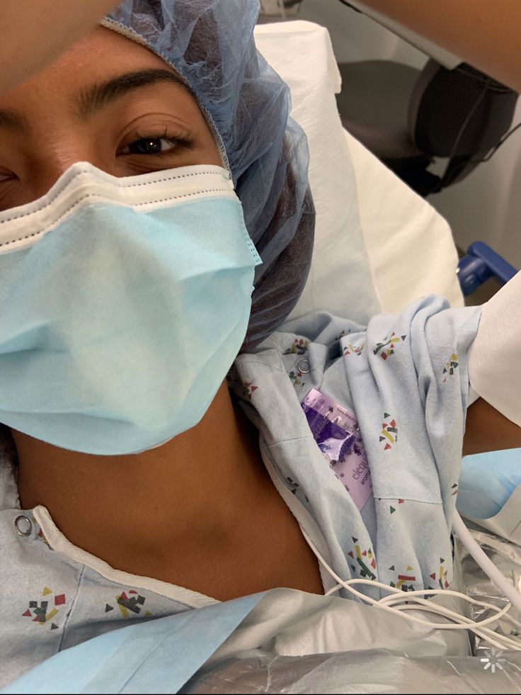 a woman in a hospital bed wearing a surgical mask