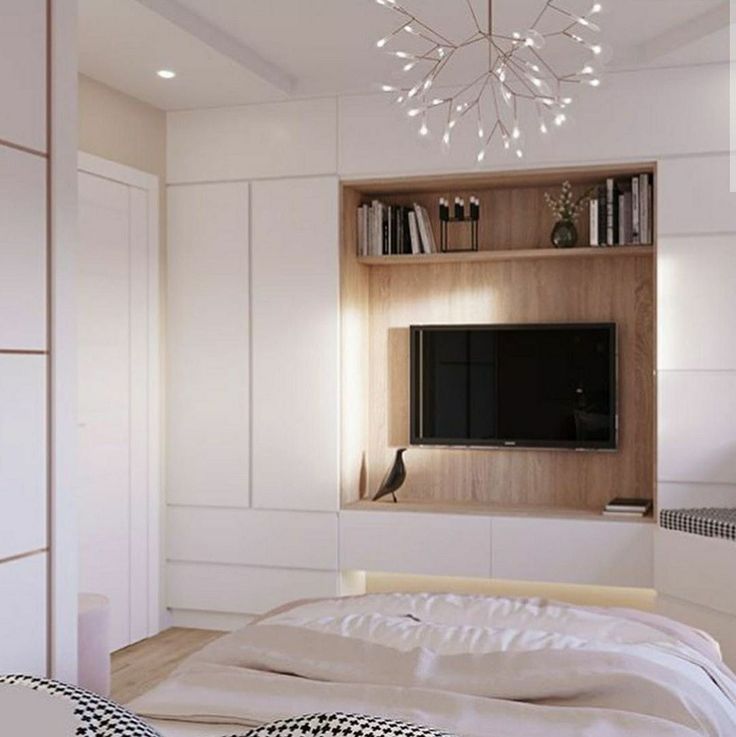 a bedroom with a bed, television and bookshelf on the wall above it