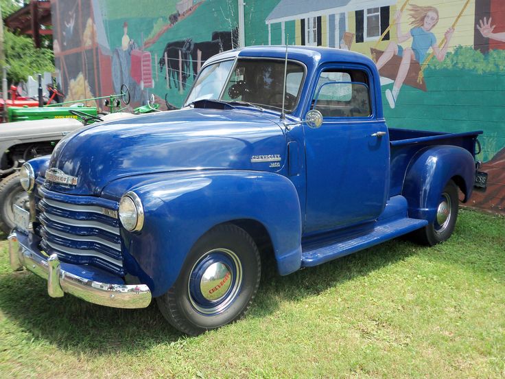 an old blue truck is parked in the grass