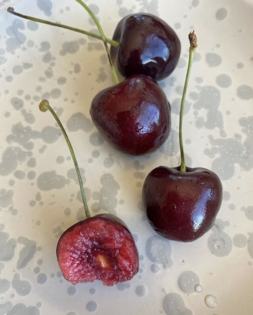 three cherries sitting on top of a white plate