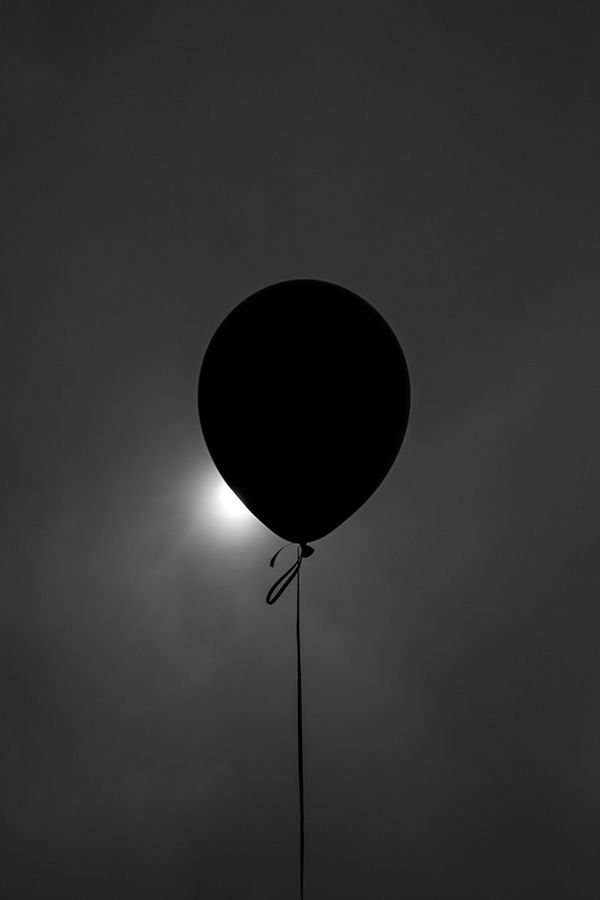 a black and white photo of a hot air balloon in the sky with the sun behind it