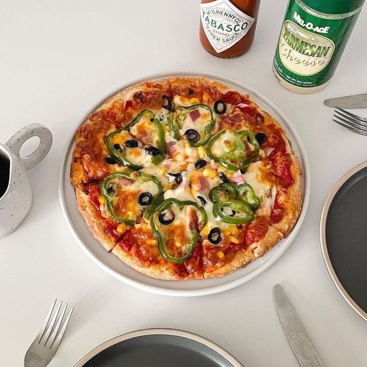 a pizza sitting on top of a white table next to silverware and utensils