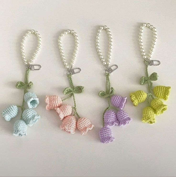 four crocheted key chains with bows and pearls hanging from each one's side