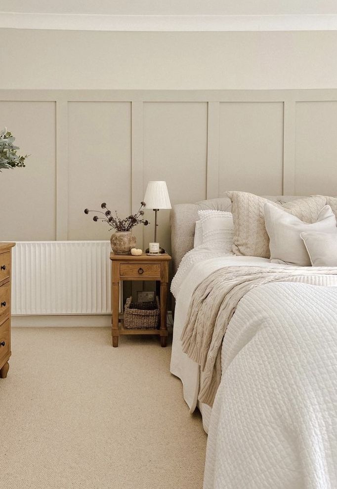 a bedroom with a bed, dresser and lamp on the side table in front of it