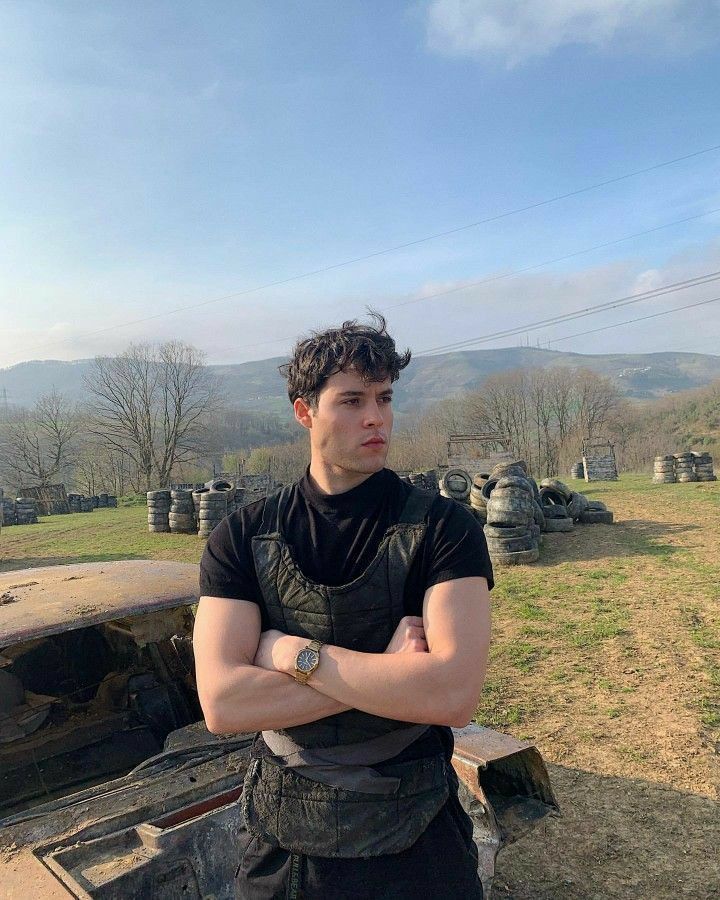 a man with his arms crossed standing in front of an old truck