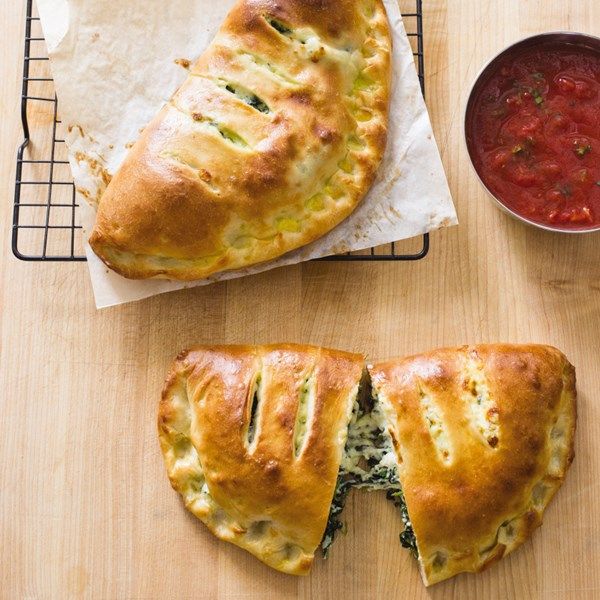 two pieces of bread sitting on top of a cutting board next to a bowl of sauce