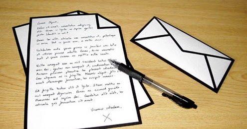 two envelopes and a pen on a wooden table next to some paper with writing