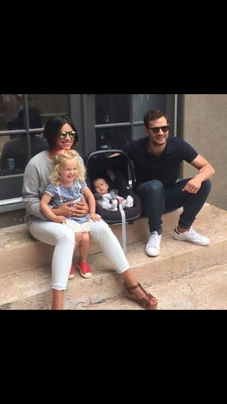 three people sitting on steps with one holding a baby and the other holding a toddler