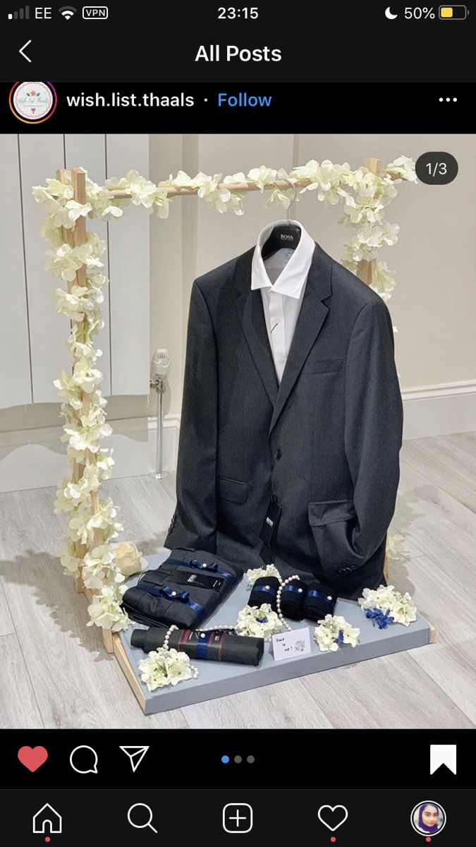 a suit and tie on display in front of a white flowered frame with flowers