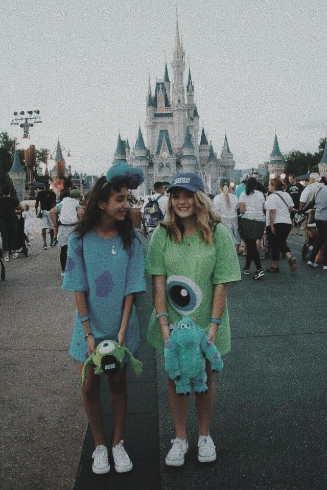 two girls standing in front of a castle with an eyeball on their face and one holding a stuffed animal