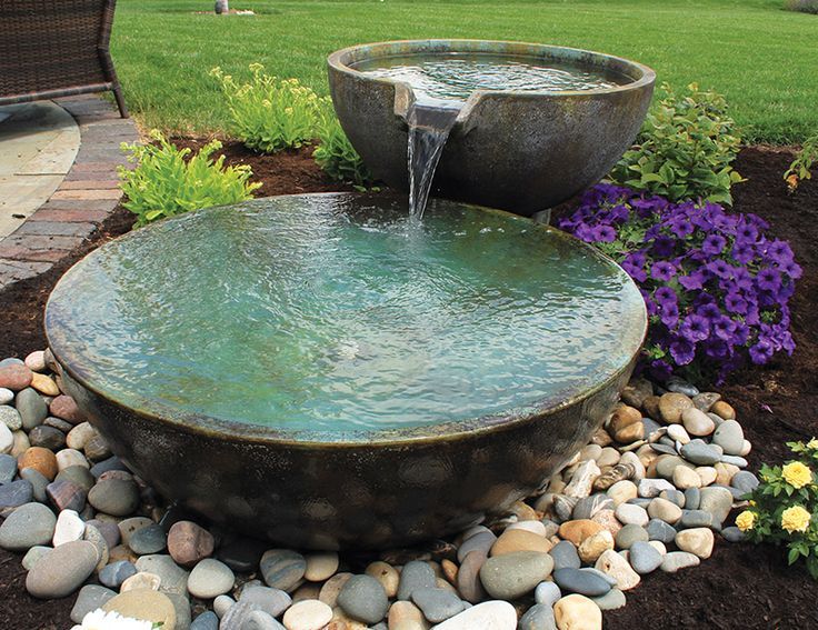 a water fountain surrounded by rocks and flowers