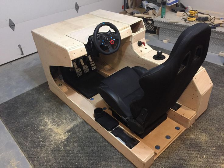 a car made out of plywood with a steering wheel and pedals on it