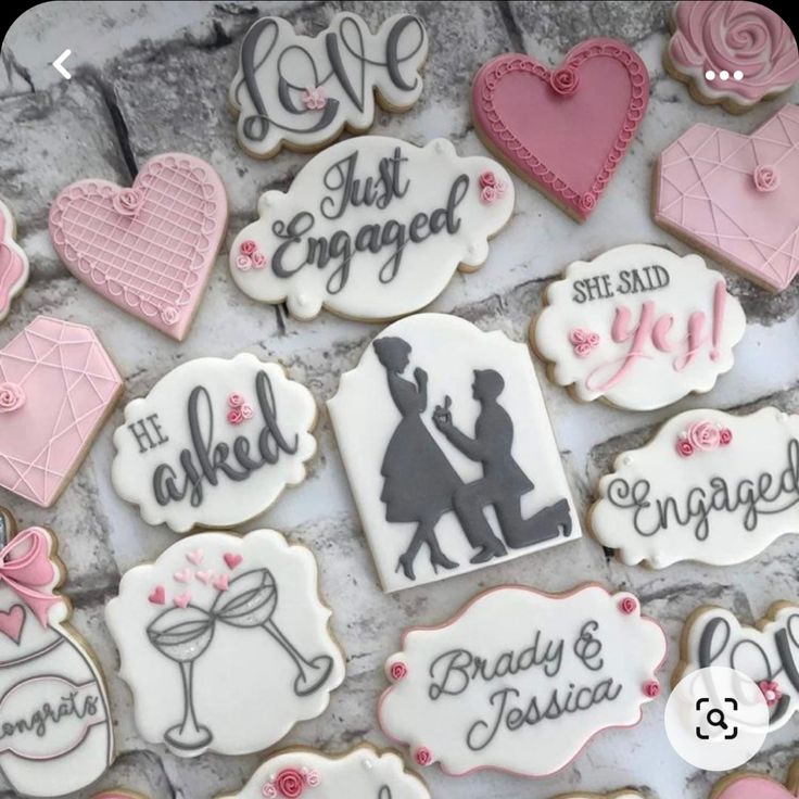 decorated wedding cookies are displayed on a stone surface with pink and gray accents, including the bride and groom's names