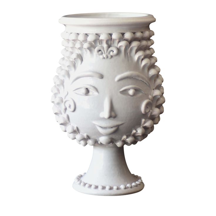 a white vase that has a face on the front and sides, with beads around it