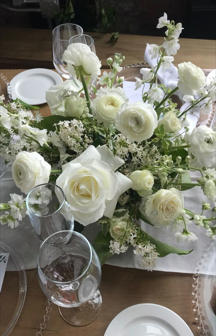 a table with white flowers and plates on it