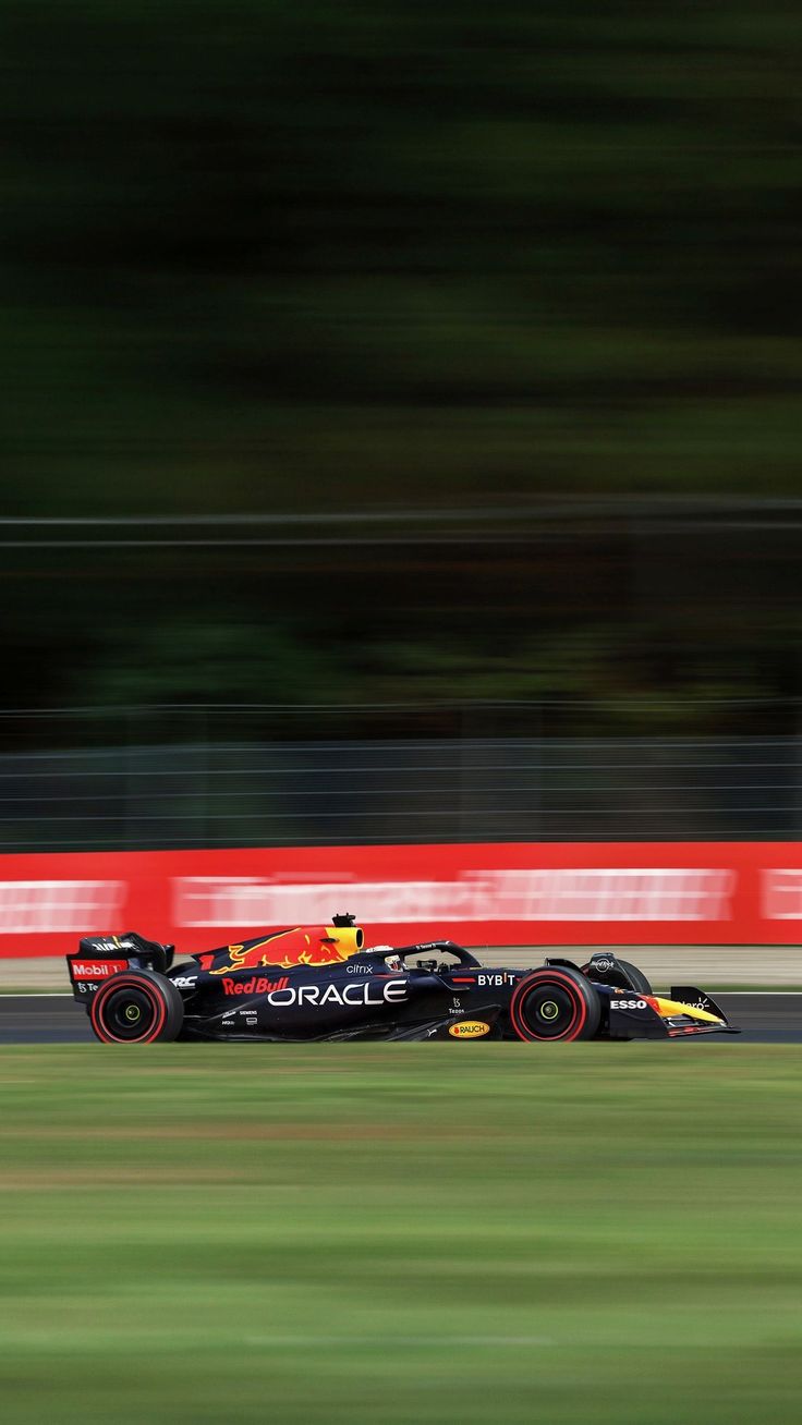 a red and yellow race car driving down the track with blurry trees in the background