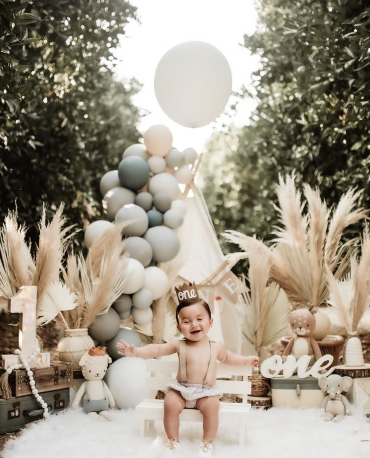 a baby is sitting on a chair in front of balloons and other decorations for a photo shoot