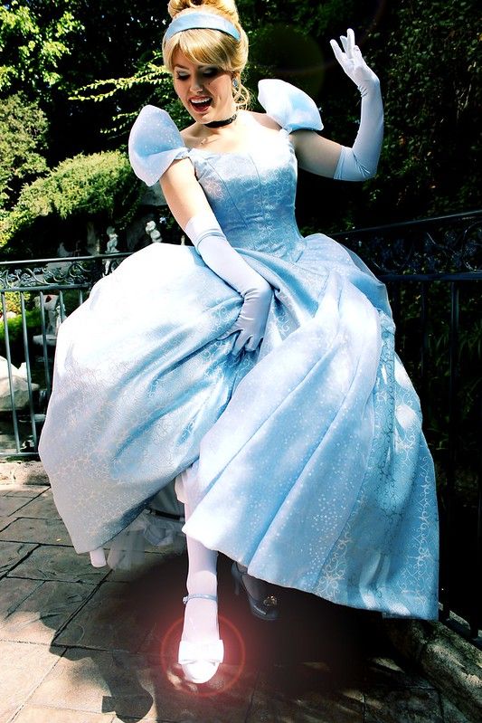 a woman in a blue dress and white gloves is posing for the camera with her arms outstretched