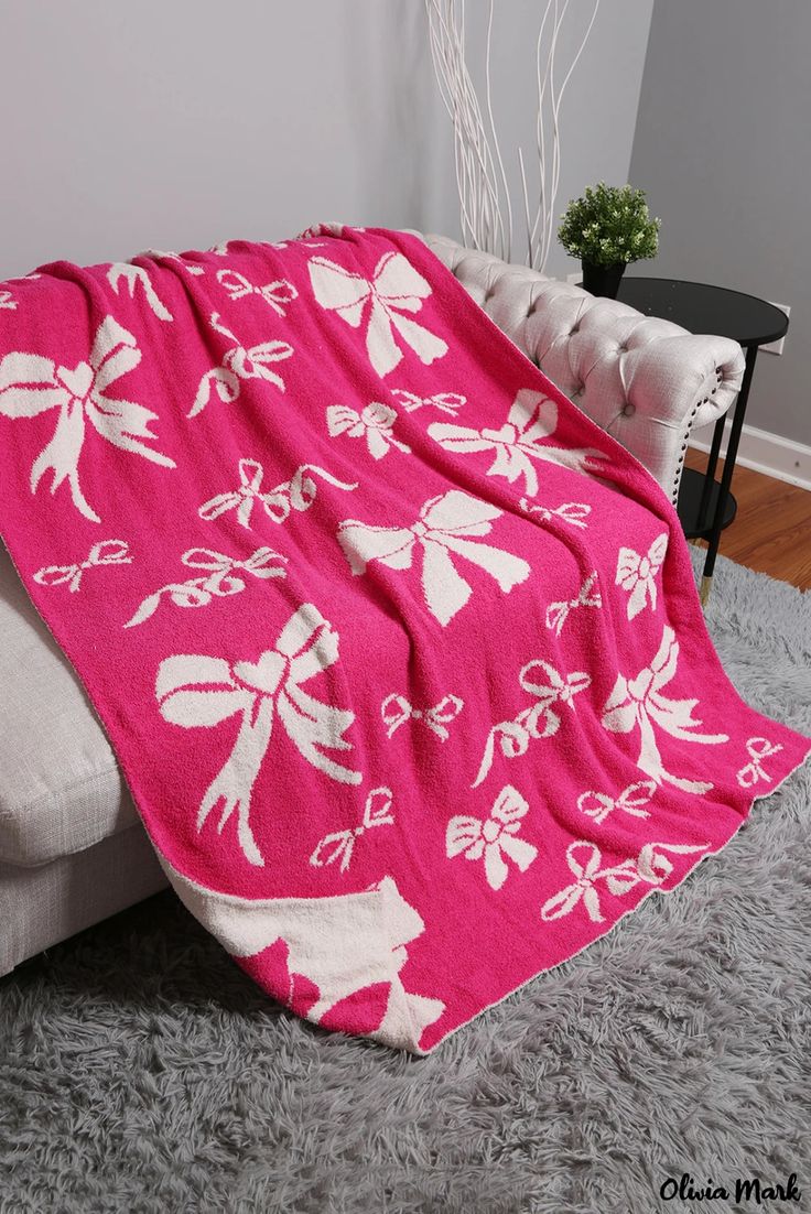 a pink and white blanket sitting on top of a couch