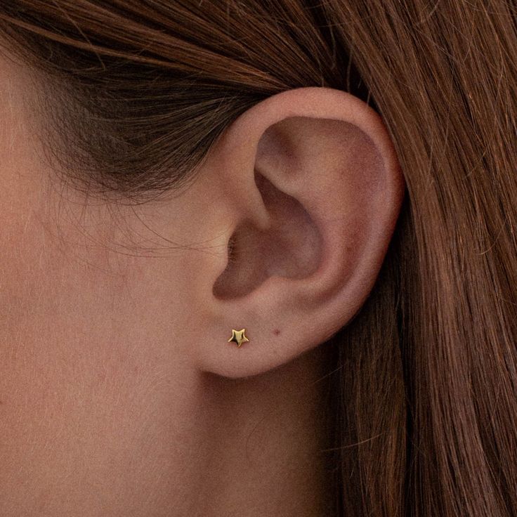 Inspired by the stars, each petite stud playfully sits on the ear with its feminine charm. Small yet curious, the Mini Star stud earrings reminisce of a starry night. - Gold Vermeil - Coated in 18K gold (2.5 microns) - Sterling Silver Base - Height: 4mm - Width: 4mm JEWELRY CARE As with all metals, special care must be taken to ensure they do not scratch or tarnish over time. Follow these simple steps to keep your pieces looking their best:Avoid direct contact when applying cosmetics, perfumes, Stud Gold Earrings, Star Stud Earrings, Small Gold Earrings, Gold Earrings Studs Simple, 2 Ear Piercings, Starter Earrings, Ear Piercing Studs, Gold Star Earrings, Mini Earrings